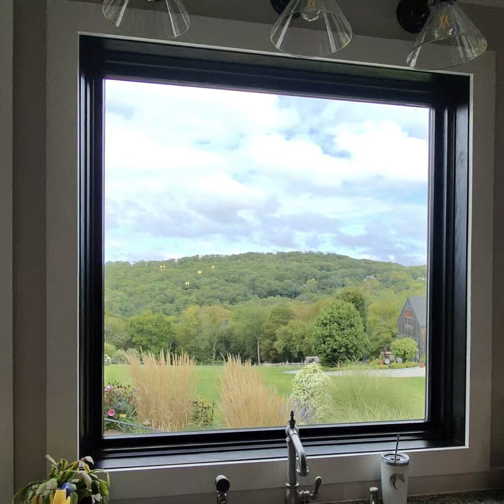 A view of fields and distant trees through a large picture window