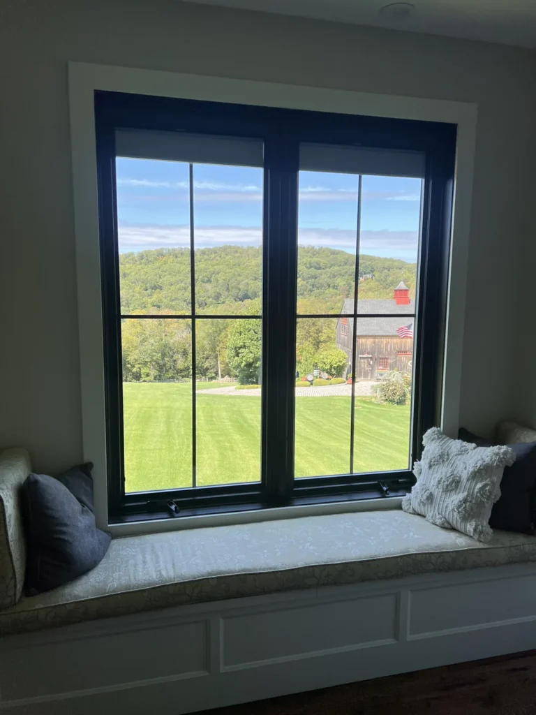Black-framed window above a window seat with a garden view