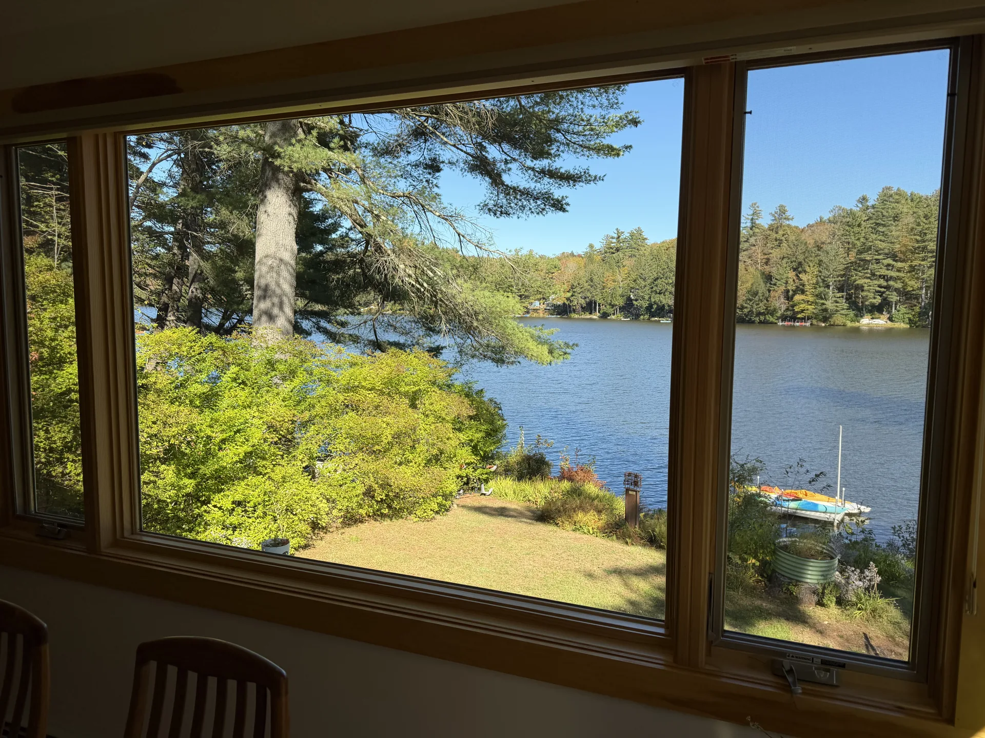 Wood-framed picture window overlooking a lake and autumn trees