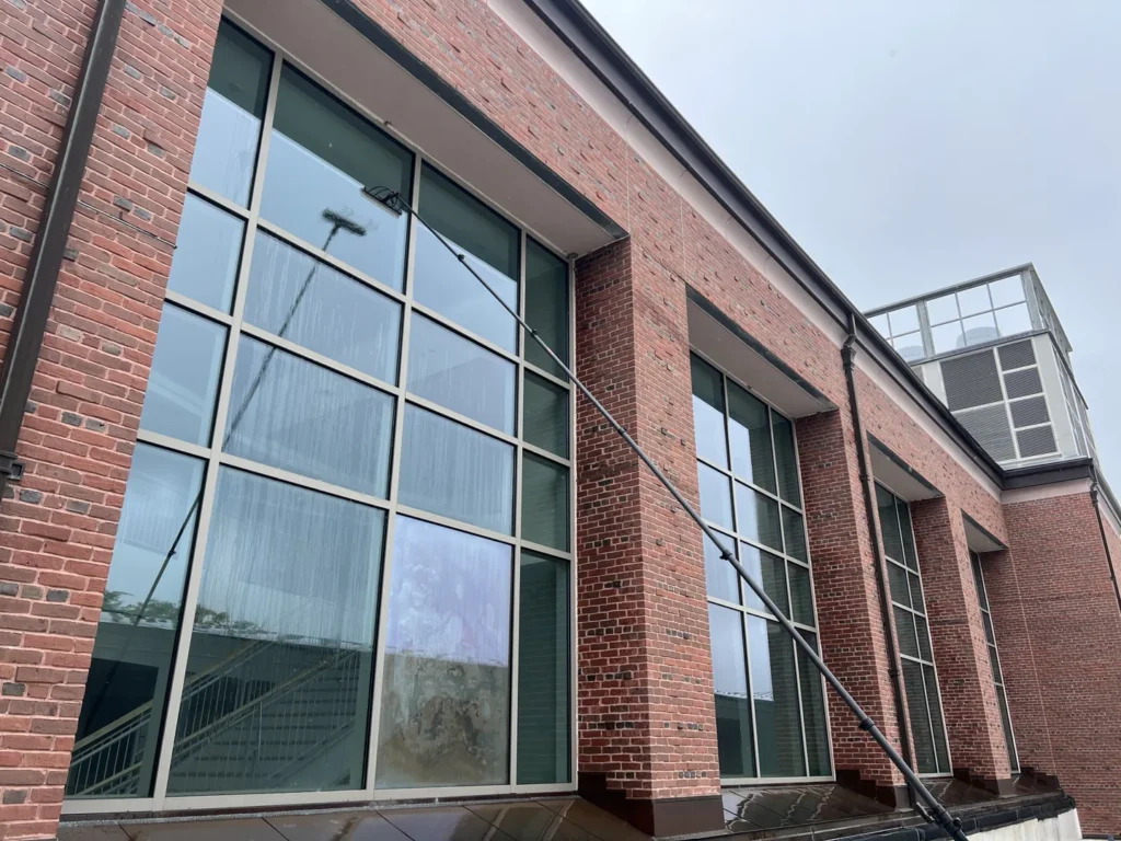 Water-fed pole cleaning large windows on a brick building