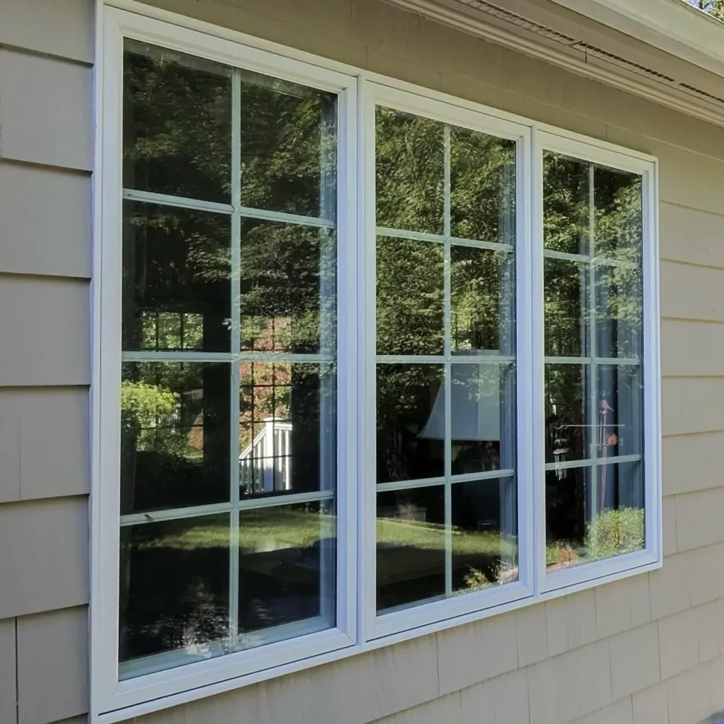 Exterior white-framed residential windows reflecting trees
