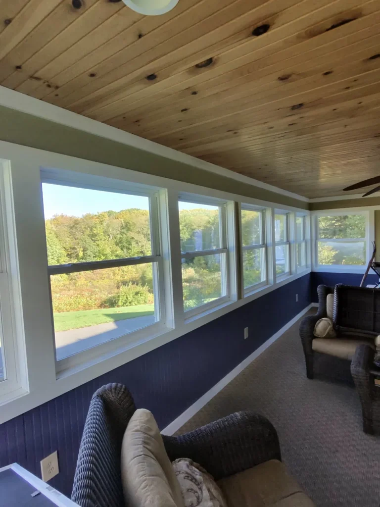 White-framed sunroom windows beneath a wood ceiling