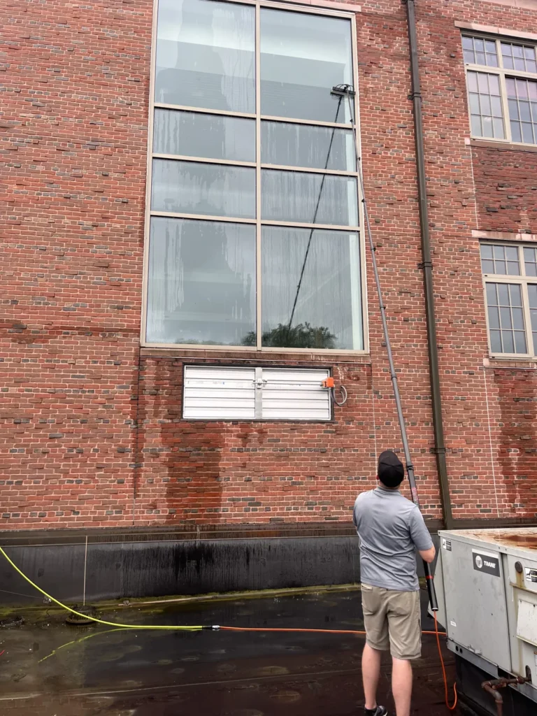 Window cleaner working on tall glass on a brick building