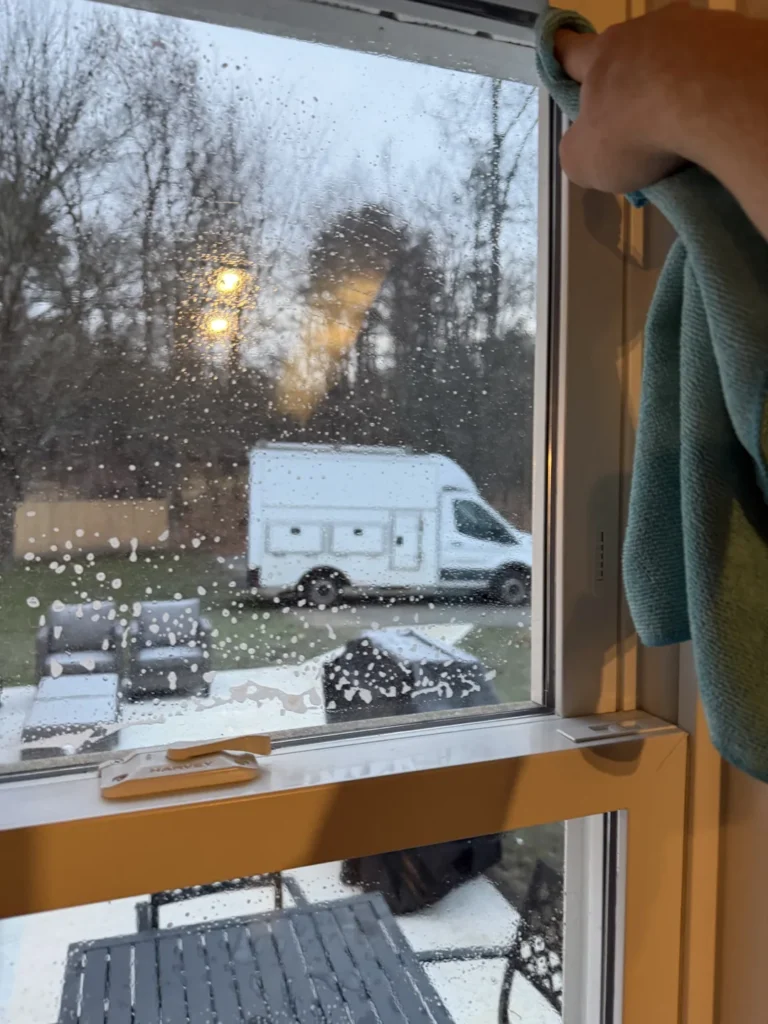Hand and towel detailing the edge of an interior window